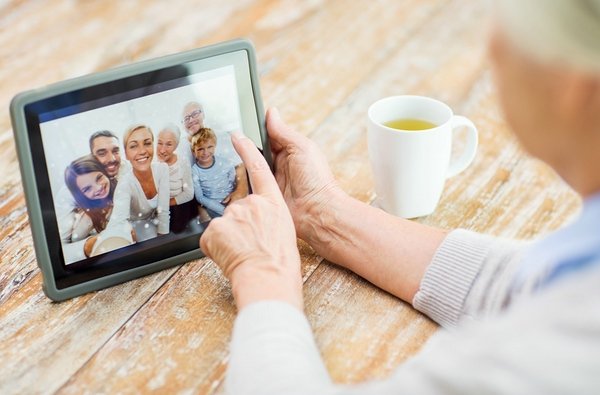 senior woman with family photo on tablet pc screen Mit digitalspezialist wertvolle Erinnerungen bewahren