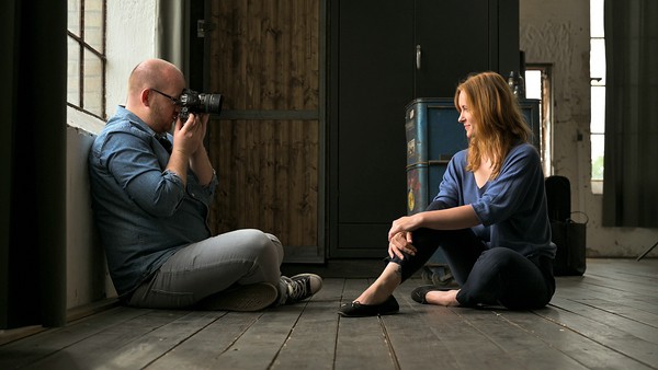 Nikon School mit neuem Herbst/Winter-Programm. Mann portraitiert Frau auf dem Boden sitzend
