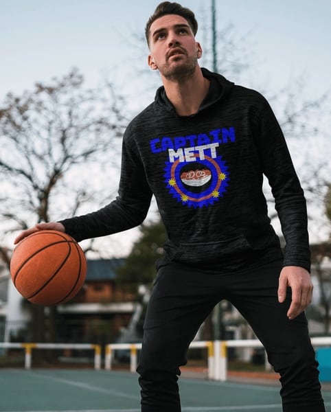Basketballspieler auf Außenfeld trägt schwarzen Hoodie mit "Captain Mett" Aufdruck