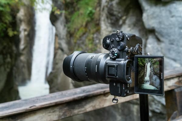 Tamron 28-200mm F/2.8-5.6 Di III RXD an Kamera auf Stativ vor Wasserfall