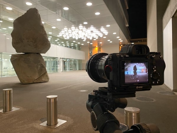 Objektiv von NWS Instruments AG 23APO an Kamera auf Stativ in Aktion in einer großen Vorhalle mit Steinskulptur