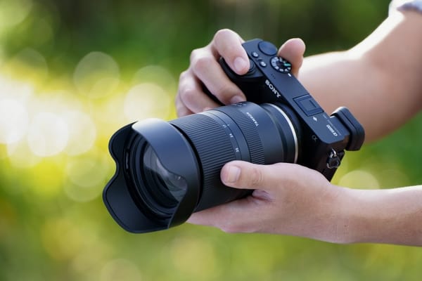 Fotograf hält mit beiden Händen eine Sony Kamera mit dem Objektiv Tamron 17-70mm F/2.8