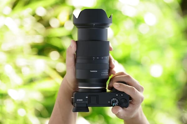 Draufsicht: Fotograf hält mit beiden Händen eine Sony Kamera mit dem Objektiv Tamron 17-70mm F/2.8