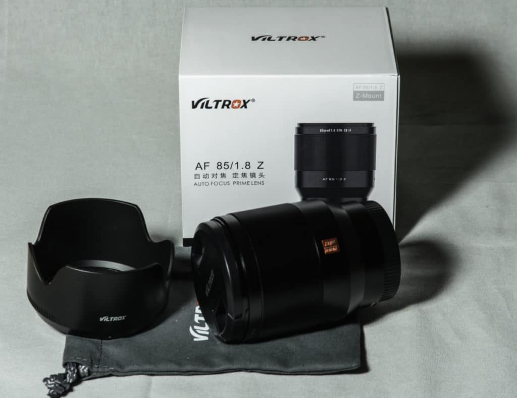 VILTROX OBJEKTIV AF 85 MM F/1.8 MIT NIKON Z-MOUNT Produktbild mit Verpackung im Hintergrund