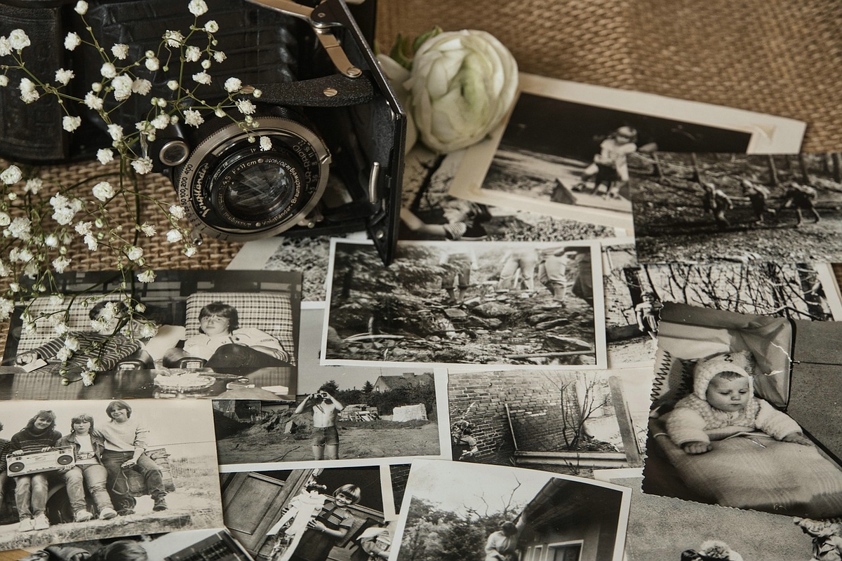Alte Schwarzweißfotografien und Familienbilder liegen neben einer historischen Kamera.