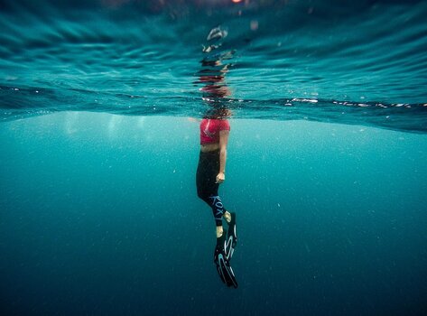 Split-Shot-Aufnahme einer Schwimmerin halb über und halb unter der Wasseroberfläche