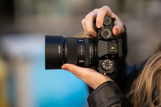 Seitenansicht des Viltrox AF 90mm F2.2 EVO XF mit Gegenlichtblende an einer kompakten Fujifilm-Systemkamera. Seitenansicht des Viltrox AF 90mm F2.2 EVO XF mit Gegenlichtblende an einer kompakten Fujifilm-Systemkamera.