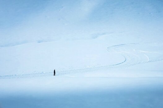 Einzelne Person in einer weiten Schneelandschaft mit großen freien Flächen als Beispiel für negativen Raum in der Fotografie. Einzelne Person in einer weiten Schneelandschaft mit großen freien Flächen als Beispiel für negativen Raum in der Fotografie.