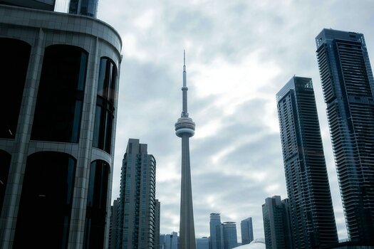 Der markante CN Tower in Toronto ragt zwischen modernen Hochhäusern unter einem dramatisch bewölkten Himmel empor. Der markante CN Tower in Toronto ragt zwischen modernen Hochhäusern unter einem dramatisch bewölkten Himmel empor.