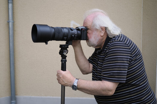 Dieter Doeblin fotografiert mit einer Kamera und Teleobjektiv im Freien.