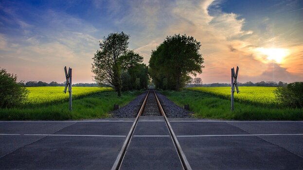 Gerade Bahngleise führen in die Ferne und symbolisieren Aufbruch, Reise und Fernweh.
