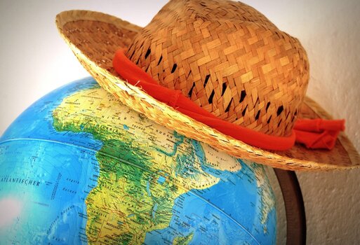 Globus und Sonnenhut stehen als Sinnbild für Reiseplanung, Abenteuer und Fernweh.