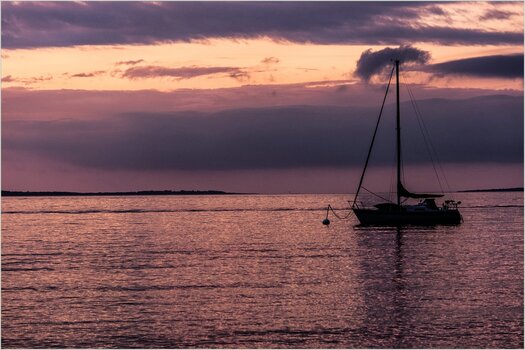 Segelboot im Sonnenuntergang auf ruhigem Wasser vermittelt Weite, Ruhe und Fernweh