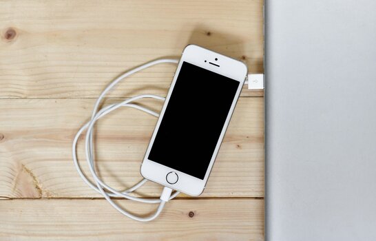 Smartphone per USB-Kabel mit einem Laptop verbunden – klassische Methode zur Übertragung von Fotos auf den Computer. Smartphone per USB-Kabel mit einem Laptop verbunden – klassische Methode zur Übertragung von Fotos auf den Computer.
