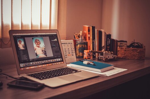 Fotografischer Arbeitsplatz mit MacBook, Lightroom und Zubehör für die Bildverwaltung.