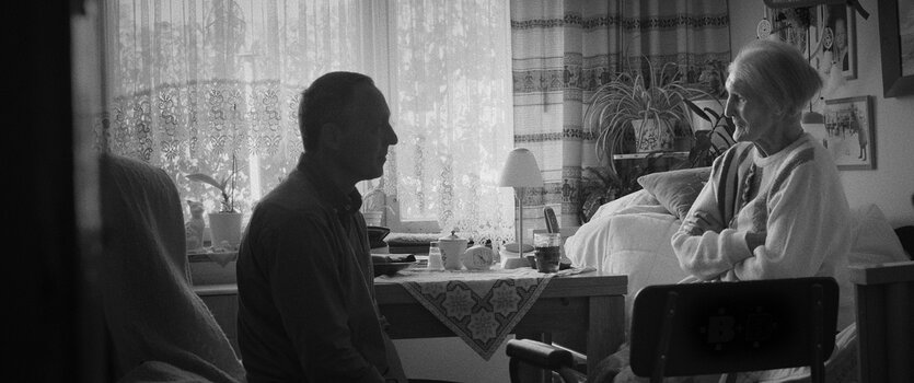 Schwarz-Weiß-Szene mit Menschen im Innenraum, aufgenommen für den Dokumentarfilm „Hiddensee“.