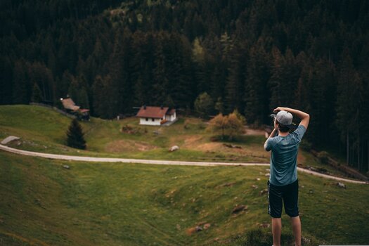 Fotograf mit Kamera vor einer weitläufigen Landschaft