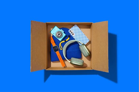 Offene Versandbox mit Kamera, Smartphone, Kopfhörern und Smartwatch Offene Versandbox mit Kamera, Smartphone, Kopfhörern und Smartwatch