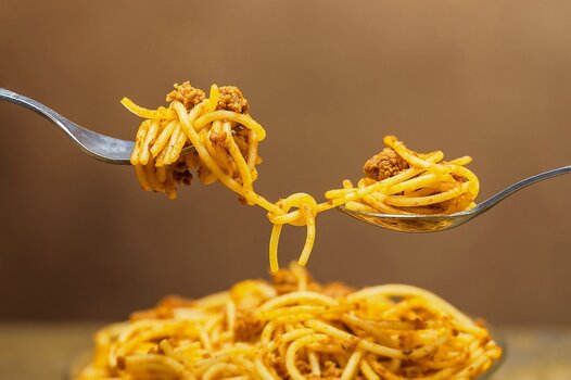 Spaghetti auf zwei Gabeln vor einem unscharfen Pastateller Spaghetti auf zwei Gabeln vor einem unscharfen Pastateller
