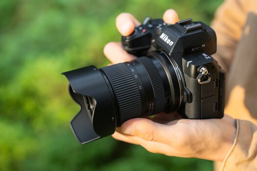 Nikon-Z-Kamera mit TAMRON 16–50mm F2.8 A in den Händen eines Fotografen. Nikon-Z-Kamera mit TAMRON 16–50mm F2.8 A in den Händen eines Fotografen.