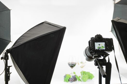 Professionelle Fotografie im Studio. Hier: Zwei gefüllte Weingläser mit Weintrauben dekoriert inklusive Studioaufbau