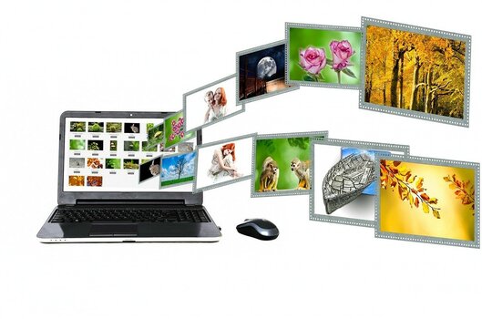 Bilder fliegen als Diaschau aus einem Laptop-Monitor heraus. Symbolbild für eigene Webseite und Internetmarketing als Berufsfotograf