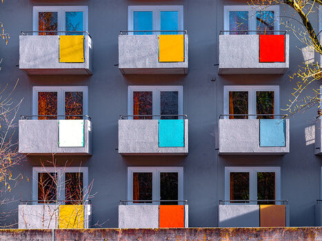 Gleichgestaltete Balkone eines Mehrfamilienhauses mit unterschiedlich bunten Teilflächen. Symbolbild für Muster.