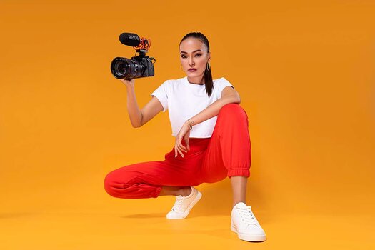 Junge Frau hält Kamera mit Richtimikrofon RØDE  VideoMic GO II in der Hand