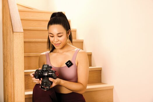 Junge Frau mit Kamera in der Hand und RØDE Wireless GO II SINGLE Version Junge Frau mit Kamera in der Hand und RØDE Wireless GO II SINGLE Version
