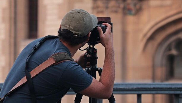 Mann fotografiert mit Kamera auf Stativ