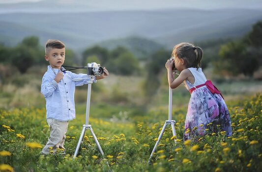 Fotografennachwuchs: Junge und Mädchen fotografieren sich gegenseitig jeweils mit Kamera auf dem Stativ