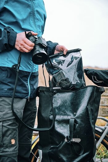 Mann steckt dry bag in Fahrradtasche Mann steckt dry bag in Fahrradtasche