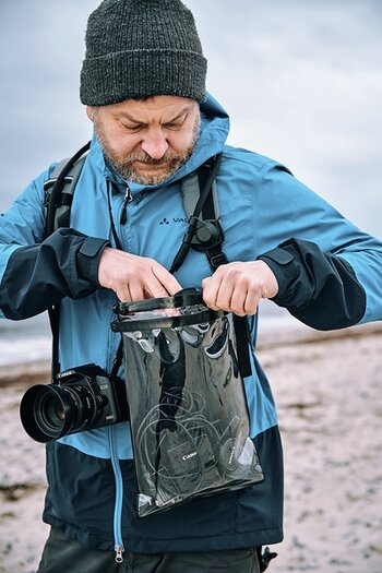 Outdoorfotograf steckt persönliche Dinge in hermetic dry bag mega