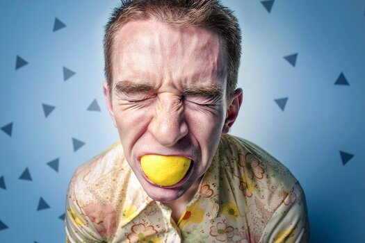 Mann beißt in ganze Zitrone