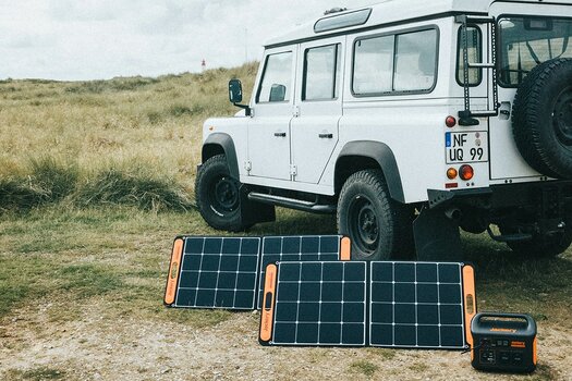 Jackery Solargenerator mit zwei Solarpanels vor einem weißen Geländefahrzeug
