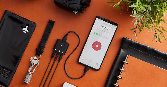 USB-C Kabel SC22 von RØDE angeschlossen an Smartphone liegt auf einem Tisch flankiert von Schlüsselband und Notizblock