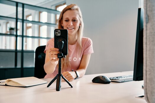 Frau positioniert die FIDLOCK VACUUM mini tripod base auf dem Schreibtisch