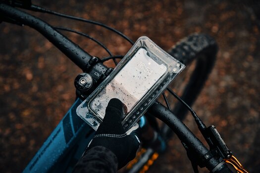 Fahrradfahrer:in tippt auf verregneten case am Lenkrad Fahrradfahrer:in tippt auf verregneten case am Lenkrad