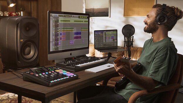 Mann sitzt am Schreibtisch, spielt Gitarre und nimmt Audio mit RØDECaster Pro II auf.