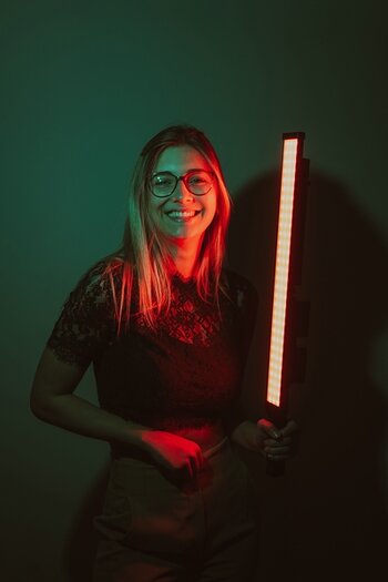 Model hält Lumen Stick RGB in der Hand und wird im dunklem Raum von diesem ausgeleuchtet. Model hält Lumen Stick RGB in der Hand und wird im dunklem Raum von diesem ausgeleuchtet.