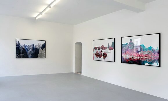 Blick in eine Ausstellung: links ein, rechts zwei Bilder nebeneinander an den Wänden