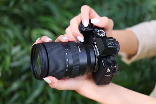 Fotografin hält Fujifilm Kamera mit angesetztem TAMRON 17-70mm F/2.8 für in der Hand Fotografin hält Fujifilm Kamera mit angesetztem TAMRON 17-70mm F/2.8 für in der Hand
