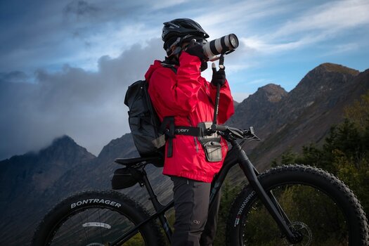 Radfahrerin steht neben ihrem Rad und fotografiert mit Kamera und Steadify Radfahrerin steht neben ihrem Rad und fotografiert mit Kamera und Steadify