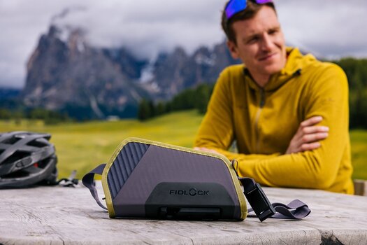 Mann sitzt draußen an Holztisch, auf dem Tisch liegt die TWIST essential bag.