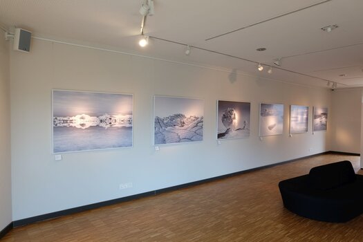 Bilderausstellung an weißer Wand mit 6 grau-weiß-blauen Naturaufnahmen