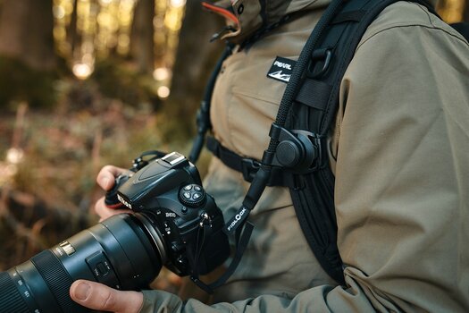 Detailbild: Fotograf trägt Kameragurt SNAPSNAP camera strap mit daran befestigter Nikon D810