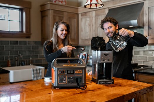 Paar in der Küche beim Kaffeekochen. Die Kaffeemaschine wird über den jackery Solargenerator Explorer 1000 betrieben. Paar in der Küche beim Kaffeekochen. Die Kaffeemaschine wird über den jackery Solargenerator Explorer 1000 betrieben.