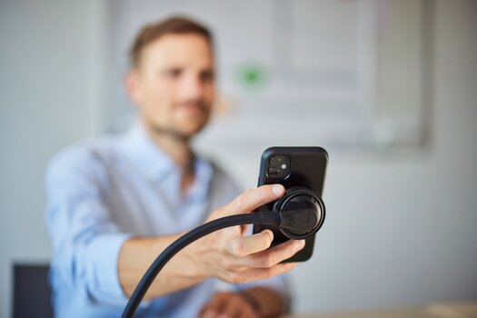 Mann löst Halterung am Vacuum flex desk base, um das Smartphone aus der Halterung zu nehmen