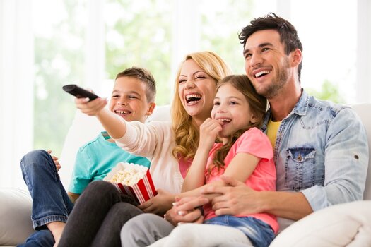 Familie sitzt auf dem Sofa und schaut einen Film