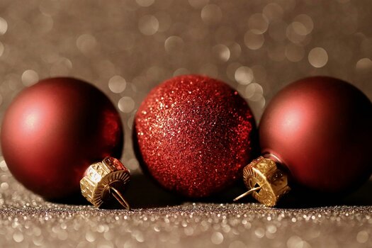 3 rote Weihnachtskugeln liegen auf glitzerndem Untergrund nebeneinander. 3 rote Weihnachtskugeln liegen auf glitzerndem Untergrund nebeneinander.